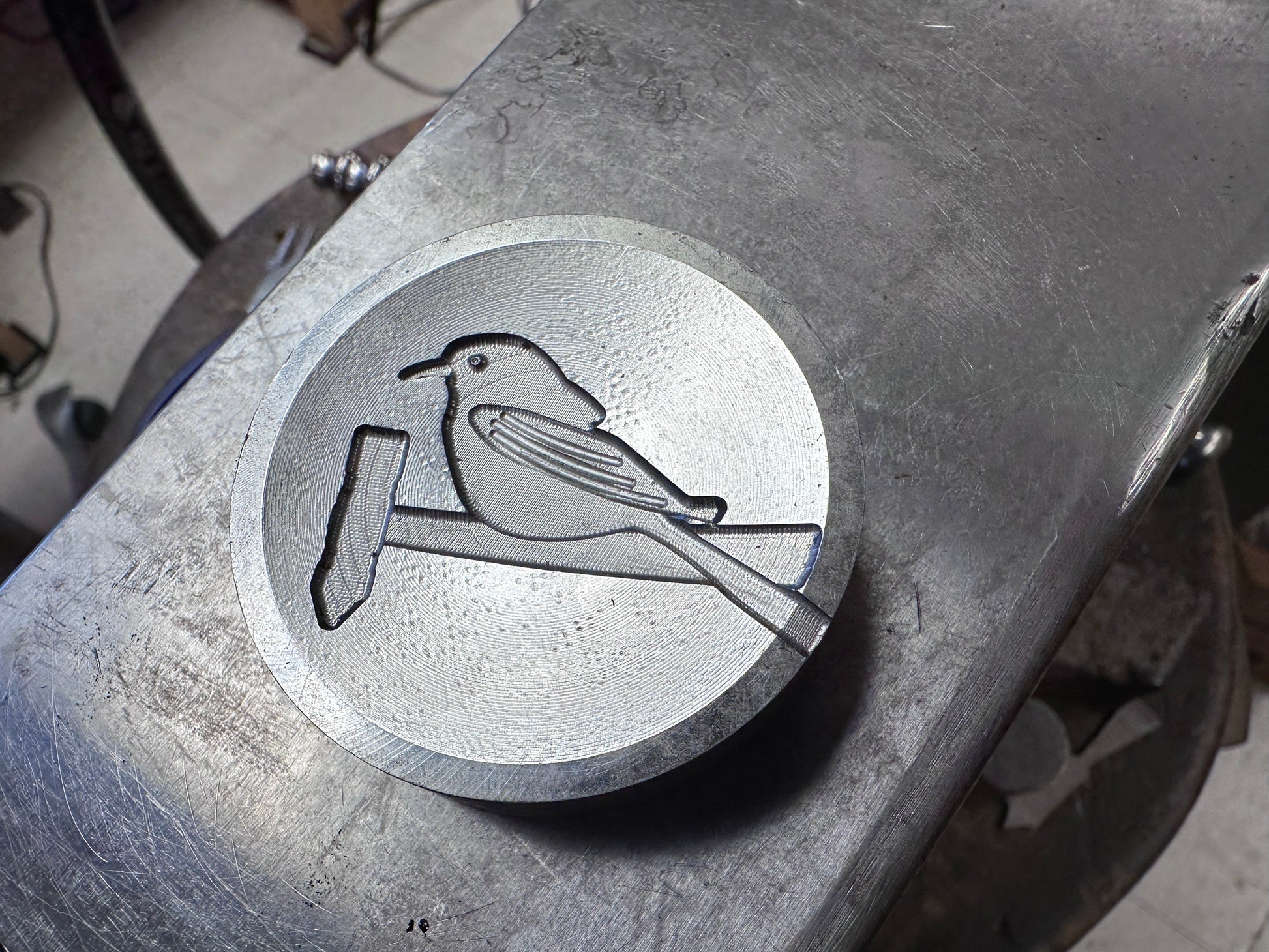 Metal die with engraved bird design on a metal surface