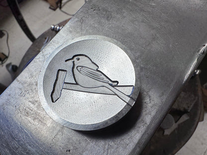Metal die with engraved bird design on a metal surface